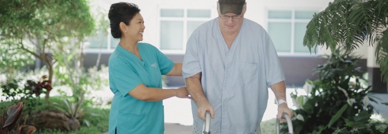 Rehab staff member assisting an elderly man in walking